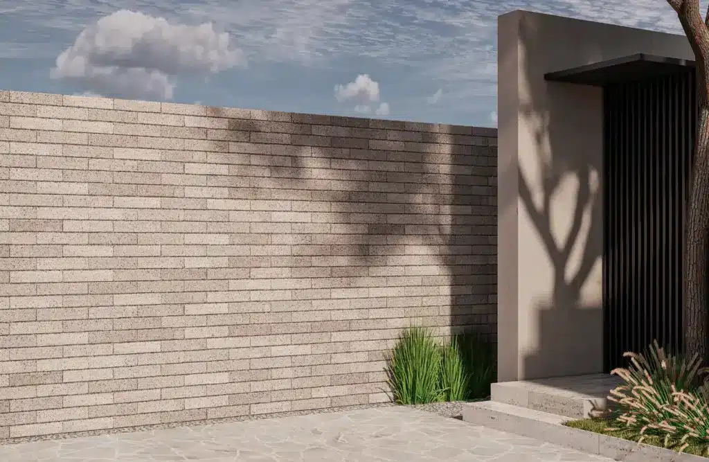 Muro de ladrillo beige con sombra de árbol y vegetación. Arquitectura moderna.