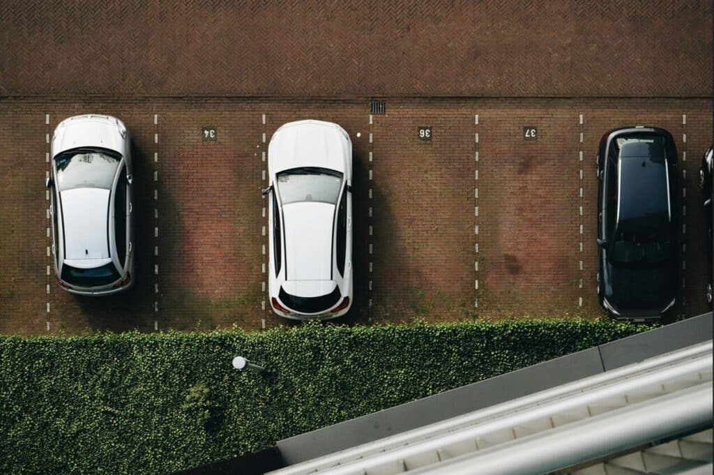 Estacionamiento con adopasto entre adoquines y autos estacionados.