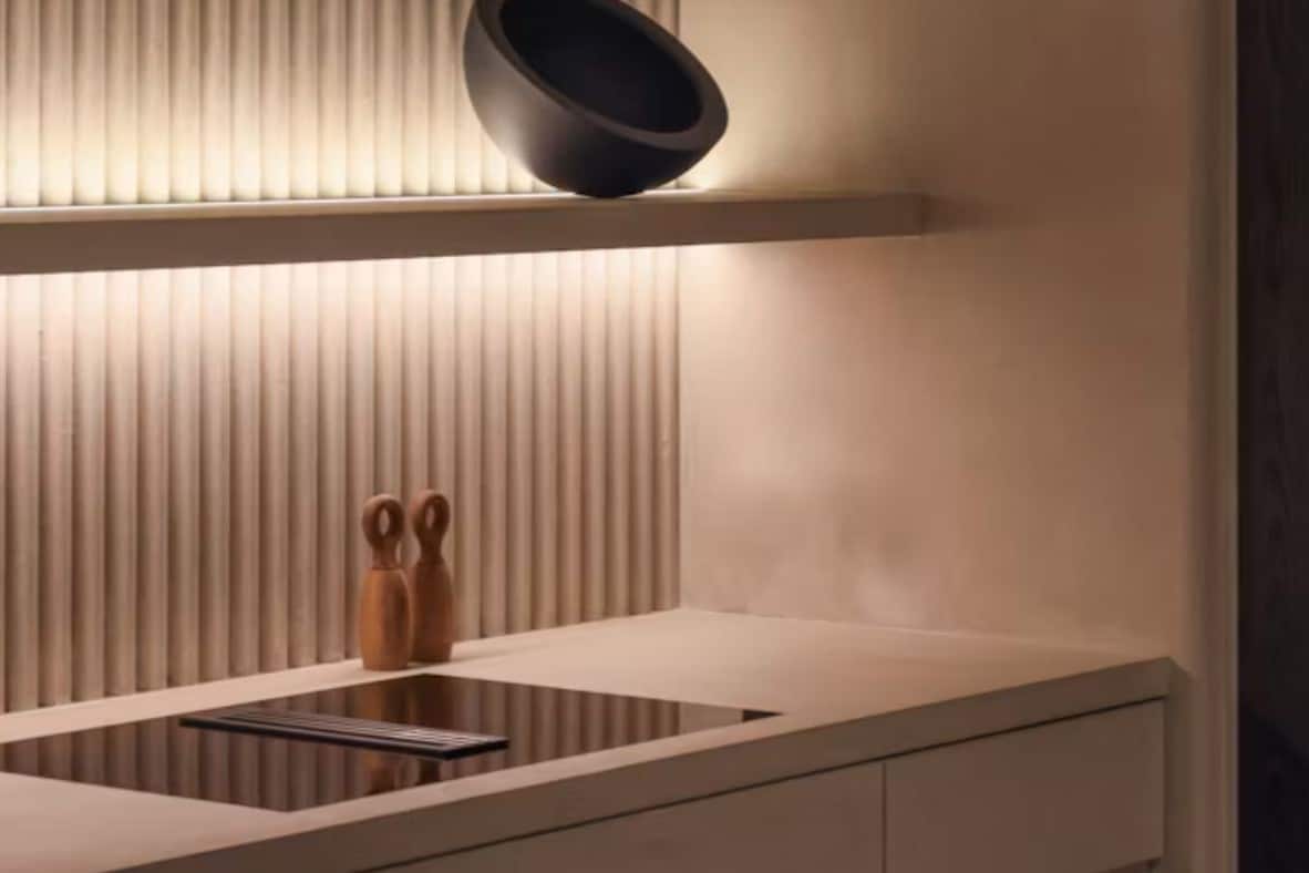 Cocina moderna con encimera de cuarzo, vitrocerámica y pared texturizada.
